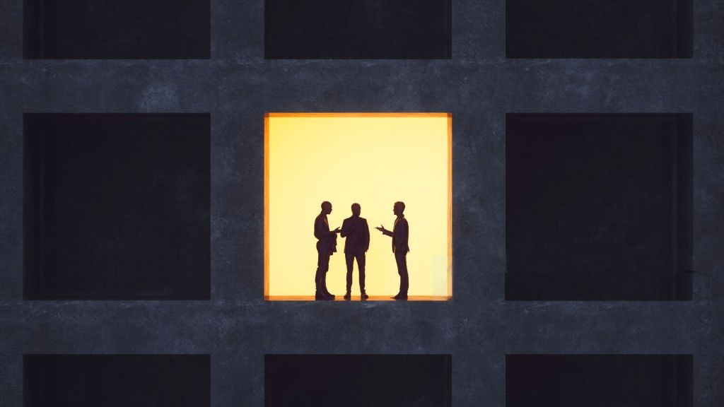 Three people talking by a window in a darkened building
